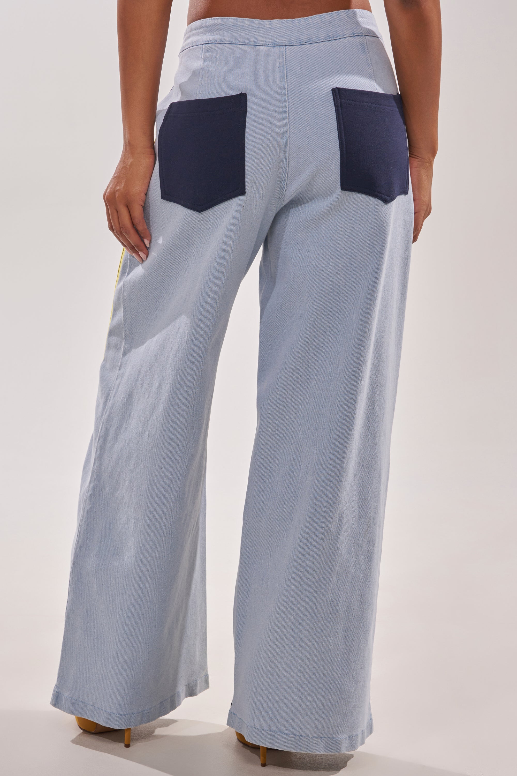 Wearing the HEADS UP DENIM WIDE LEG JOGGER IN NAVY with contrasting dark blue back pockets, a person is shown from the waist down and behind, giving their outfit a sporty vibe. 4