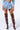 A person wearing a light blue cropped jacket and NO APOLOGIES DENIM SHORTS in a high-rise, medium-wash. They also have on distinctive brown thigh-high boots adorned with star-shaped embellishments, standing against a plain background. The person’s face is not visible in the image.