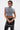 Wearing the ABLE TO SEE ME STRAPPY TOP, a person with short, dark hair and sunglasses styles it with black faux leather pants featuring grommets and a black handbag with silver buckles against a plain white background.