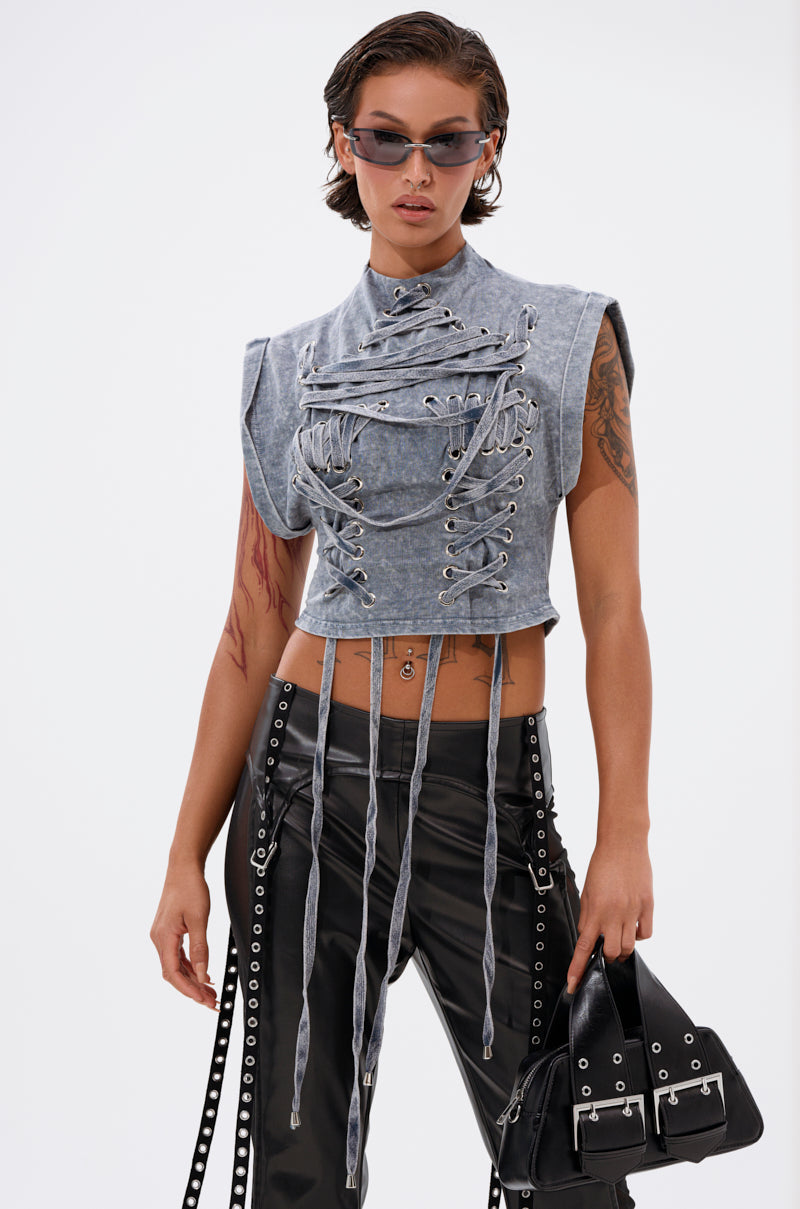 Wearing the ABLE TO SEE ME STRAPPY TOP—a gray lace-up crop top with hanging ties—paired with black grommet-detail pants, dark sunglasses, and a black handbag, this streetwear look pops against a plain white background. 2
