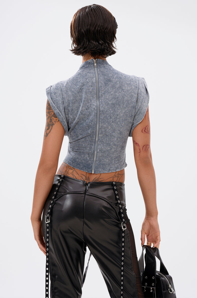 A person with short, wet-look hair is seen from behind wearing the ABLE TO SEE ME STRAPPY TOP in gray with cap sleeves and a zip-up front, paired with black high-waisted faux leather pants with strap details. Tattoos show as they hold a black handbag. 4