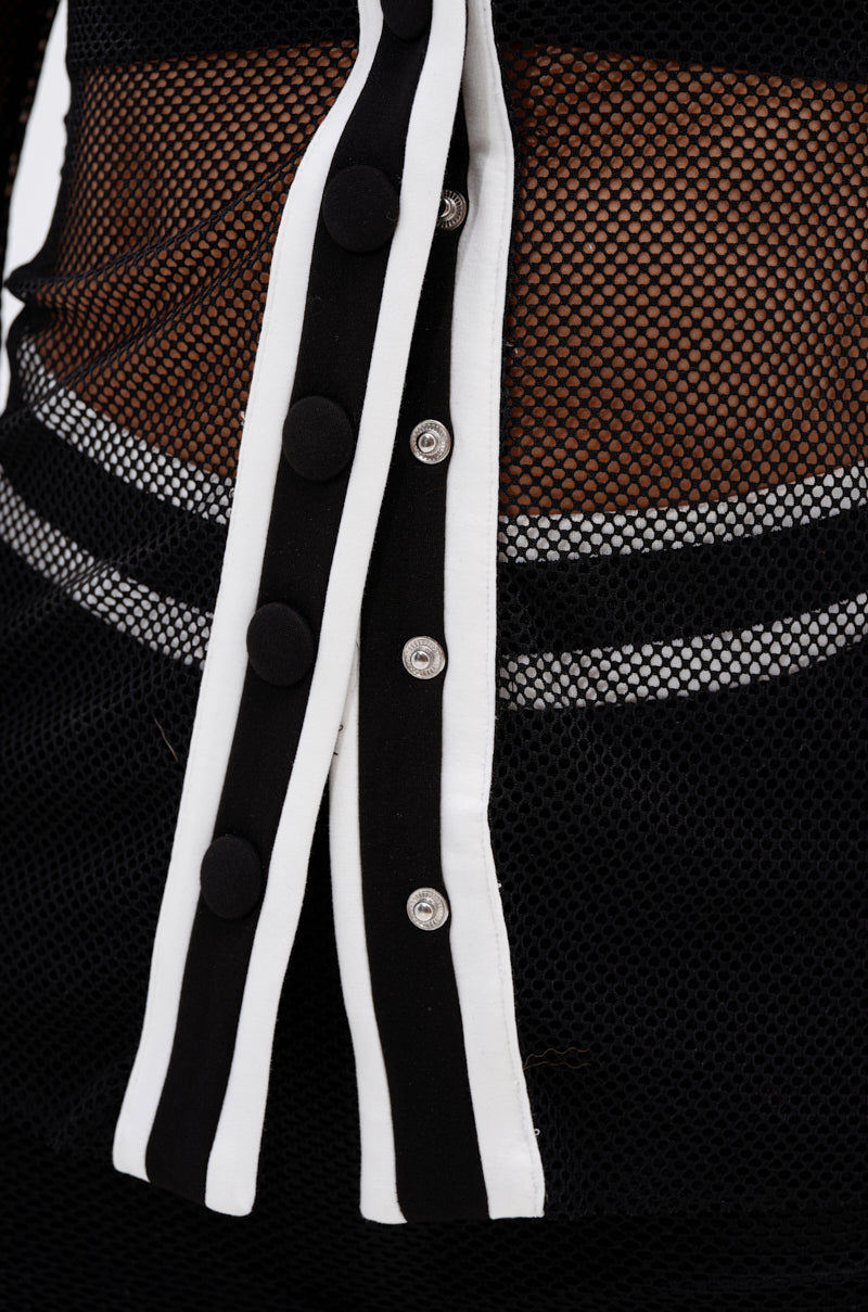 Close-up of the CANT GET ENOUGH MESH BUTTON DOWN featuring sheer mesh fabric, black-and-white striped trim, black fabric-covered buttons, and exposed snap fasteners for a sporty-chic look.