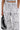 A person wears the SET YOU FREE PALAZZO PANT, a high rise white pant with bold black abstract swirls and dots, holding a black handbag. Only the lower torso and part of the hand are shown.