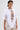 A woman in the SLASHED UP OVERSIZED SHORT SLEEVE TEE shows off a chest tattoo, styled with hoop earrings, layered silver necklaces, slicked-back short hair, and beige pants for an edgy look.