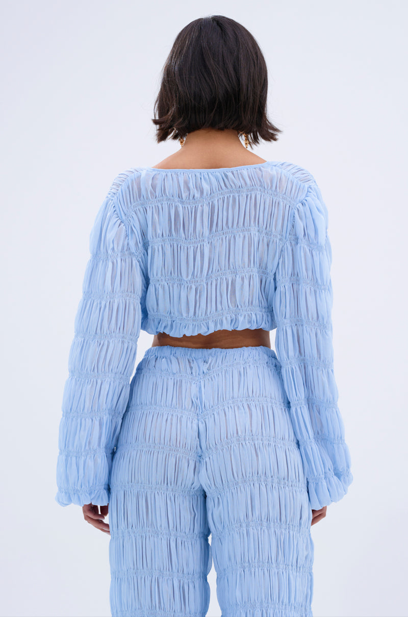 A person with short dark hair, seen from behind, wears the ICED OUT TIE FRONT TOP in light blue sheer chiffon with matching high-waisted pants against a plain light background.