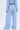 A person stands facing away, wearing a light blue, textured long-sleeve top and ICED OUT PALAZZO PANT featuring a ruched, crinkled pattern. Only their torso and legs are shown against a plain background.