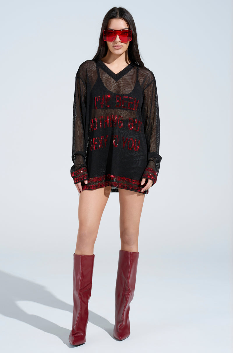 A person in an oversized silhouette features the "I HAVE BEEN NOTHING BUT SEXY TO YOU" jersey, black shorts, bold red knee-high boots, and large rhinestone-embellished sunglasses against a plain backdrop.