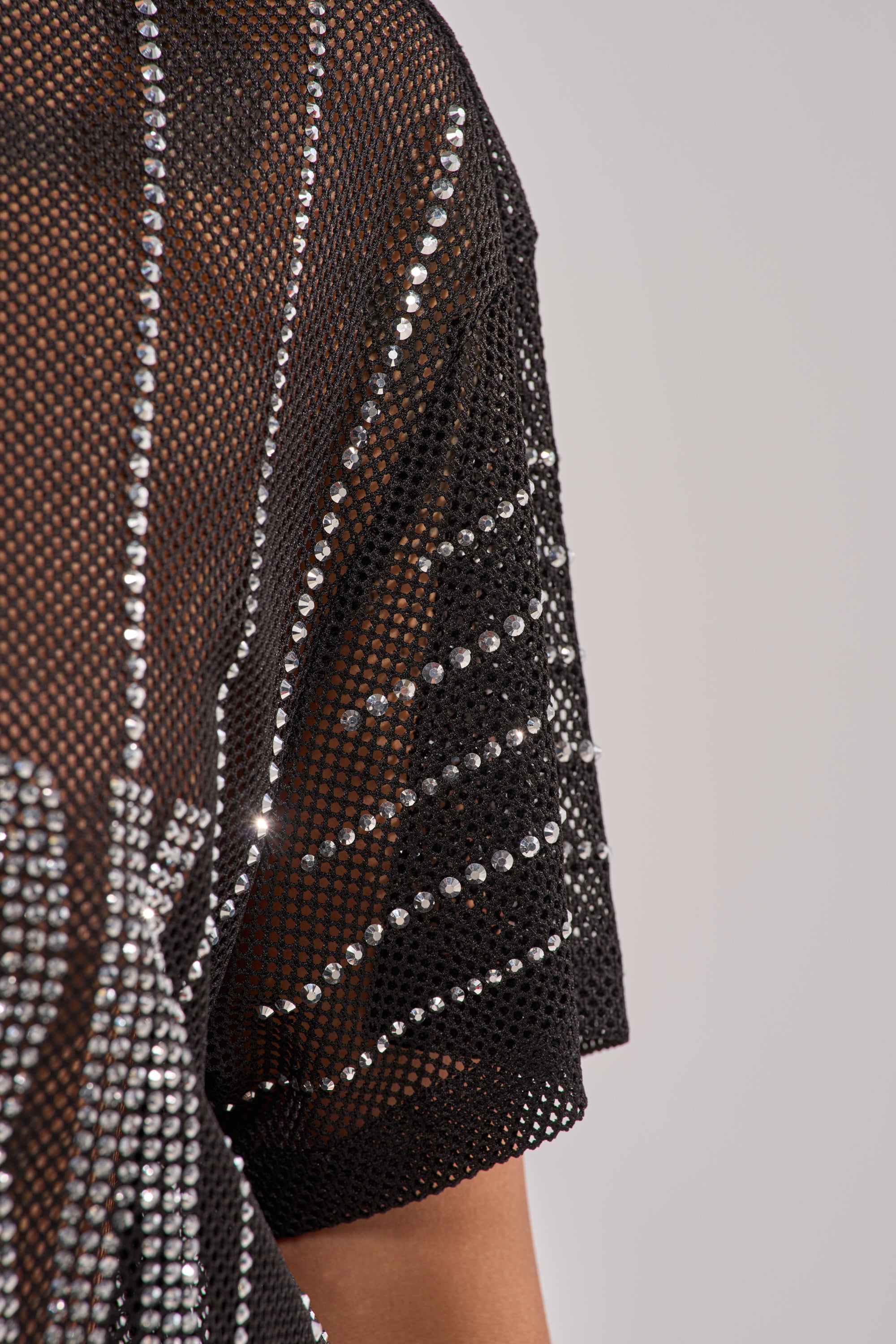 Close-up of the NEW YORK JERSEY's black bedazzled mesh sleeve, featuring rows of rhinestones and sparkling stripe detailing against a light gray background. 14