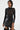 Wearing the NOT MY FAULT LONG SLEEVE MESH BODYSUIT with circular patterns paired with a black leather skirt featuring large pockets, their shoulder-length hair and hoop earrings stand out gracefully against a plain background.