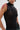 Someone wears the NOT MY FAULT SLEEVELESS BODYSUIT IN BLACK, a sheer black mesh piece with shiny circular patterns, pairing it with silver hoop earrings, a nose ring, lip piercing, and red drip body paint against a plain light backdrop.