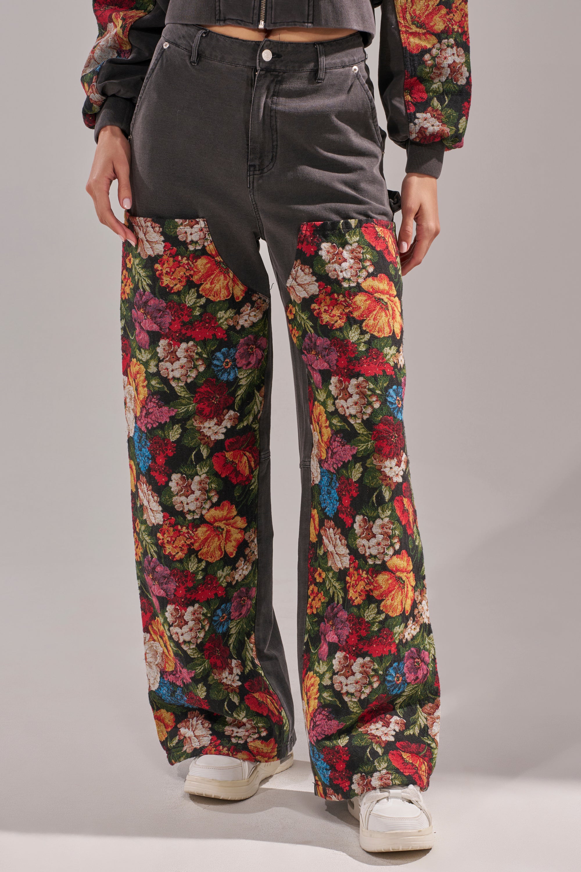Wearing the TRY ME FLORAL DENIM high-waisted, wide-leg jeans with black denim accents and floral print panels, styled with white sneakers and a matching floral jacket. 1