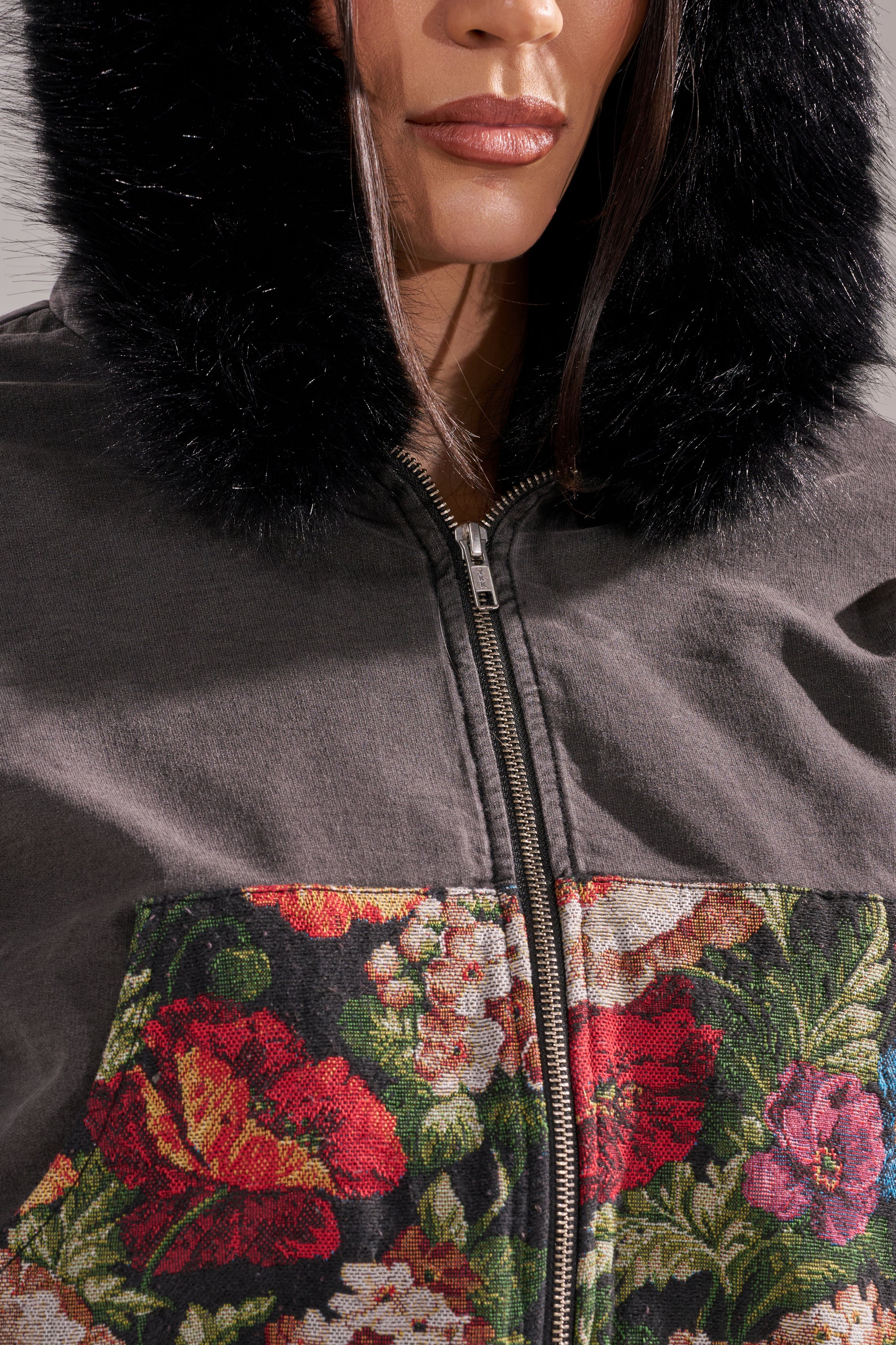 A woman wears the TRY ME FLORAL DENIM ZIP UP SWEATSHIRT, a cropped hoodie with a faux fur hood, zip-up front, and floral pattern of red and white flowers on the chest. Her face is partially visible. 11