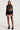 Dressed in the Moments in Time gloved lace bodysuit with elegant rhinestone embellishments, a person showcases a chic ensemble. The sheer long-sleeve top exudes sophistication with its structured accents, while the ruffled mini skirt brings an added touch of flair. The look is completed with black thigh-high stockings and platform heels, as they stand confidently against a plain background.