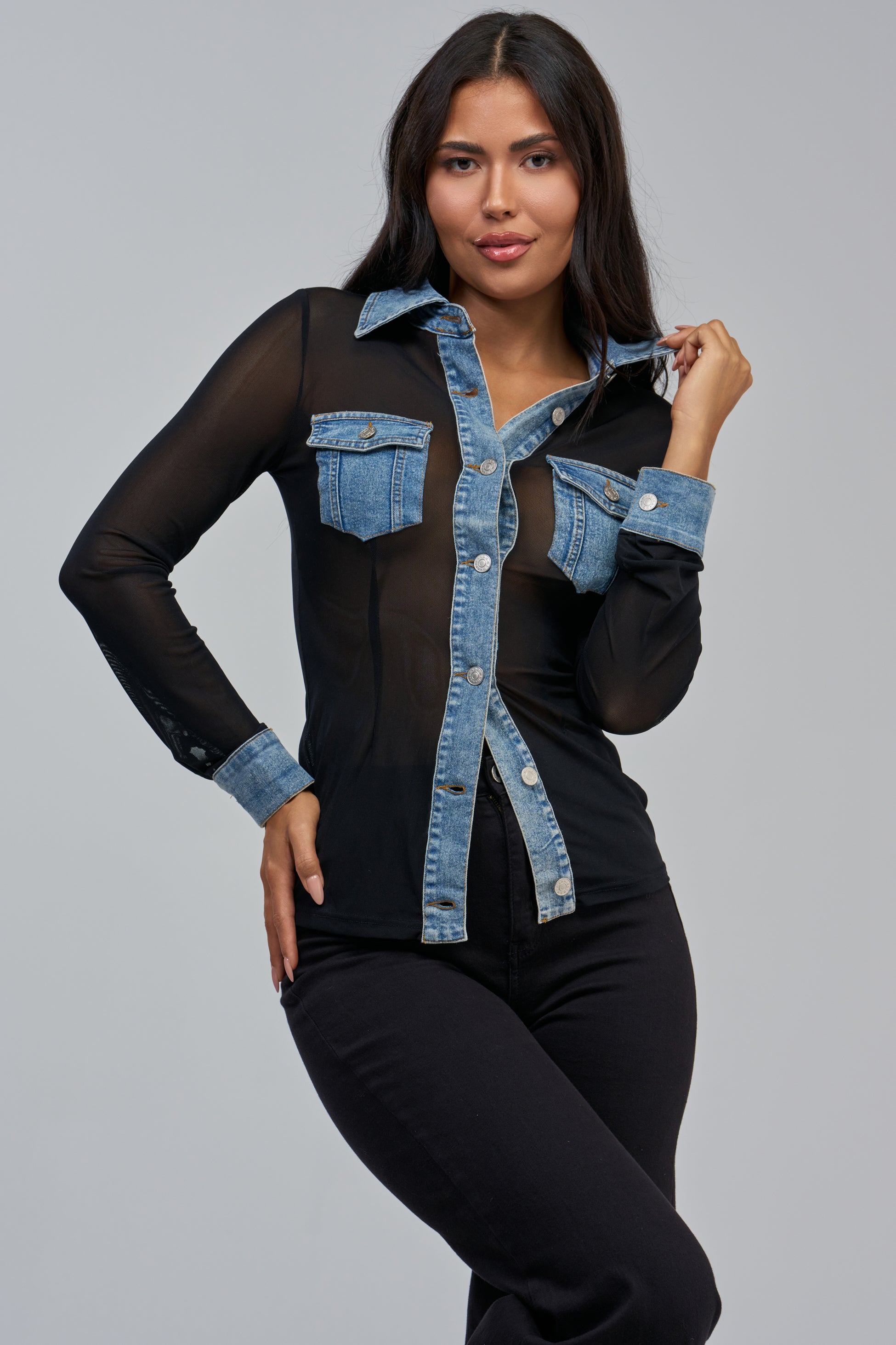 A woman models the CAMILLA MESH BUTTON DOWN—a sheer black mesh top featuring denim trim on the collar, cuffs, and pockets—styled with black pants, exuding effortlessly cool streetwear vibes against a minimalist light gray backdrop.