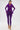 A woman poses confidently in a fitted, bright purple PUMPED UP FEATHER BLOUSE with feather trim on the top and wrists, paired with gold chain high-heeled sandals against a plain white background.