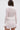 Someone wearing the ICY HOT FEATHER BLOUSE, a sheer mesh top featuring feather trim on the collar, cuffs, and waist, stands with their back to the camera against a plain light background.