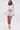 A woman models the ICY HOT FEATHER BLOUSE, a sheer mesh long-sleeve top with feather trim, styled with a matching sheer mini skirt and white high-heeled sandals, against a plain white background.