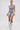 A woman stands against a white background wearing the DIVALICIOUS DENIM SHORT—a blue denim crop top and matching shorts with silver fringe, rhinestone details, floral embroidery, large earrings, and silver fringe cowboy boots.