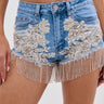 A close-up of a person wearing the DIVALICIOUS DENIM SHORT, high-waisted Western-style shorts with silver bead and sequin floral embroidery, rhinestone details, and beaded fringe along the hem.
