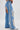 Wearing DIVALICIOUS DENIM CHAPS IN LIGHT BLUE, featuring intricate silver embroidery, rhinestone chain link fringe on sides and back, large outer thigh cutouts, and paired with silver pointed boots.