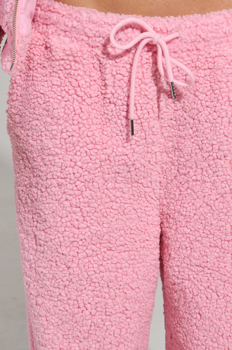A close-up of the SOUR CANDY SHERPA JOGGER showcases its pink sherpa fleece and drawstring waist, offering a soft and cozy feel ideal for loungewear.