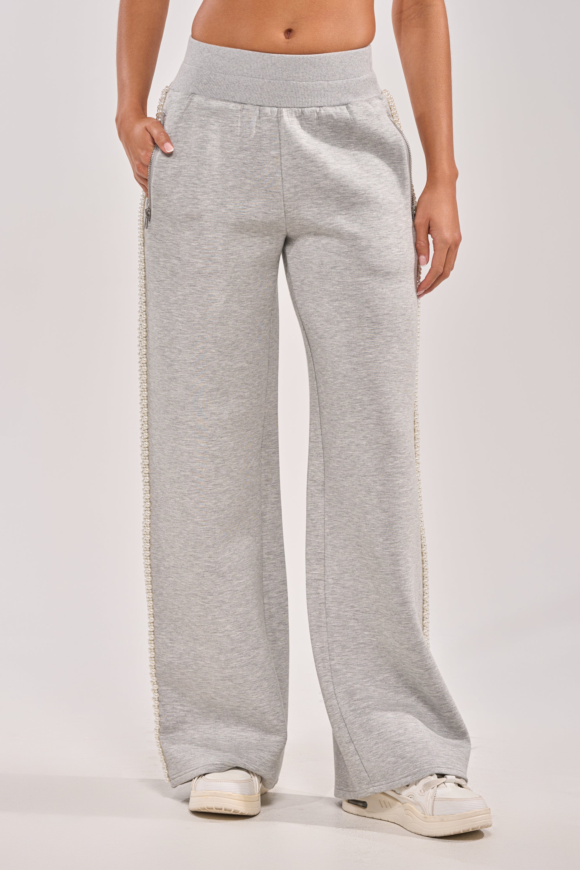 A person is shown from the waist down wearing PEARL GIRL WIDE LEG JOGGER IN GREY, featuring side pockets, paired with white sneakers against a plain background. 3