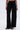 A person wearing the PEARL GIRL JOGGER—black wide-leg sweatpants with zipper pockets and pearl details along the side seams—paired with black open-toe sandals. The photo is cropped from the shoulders down.