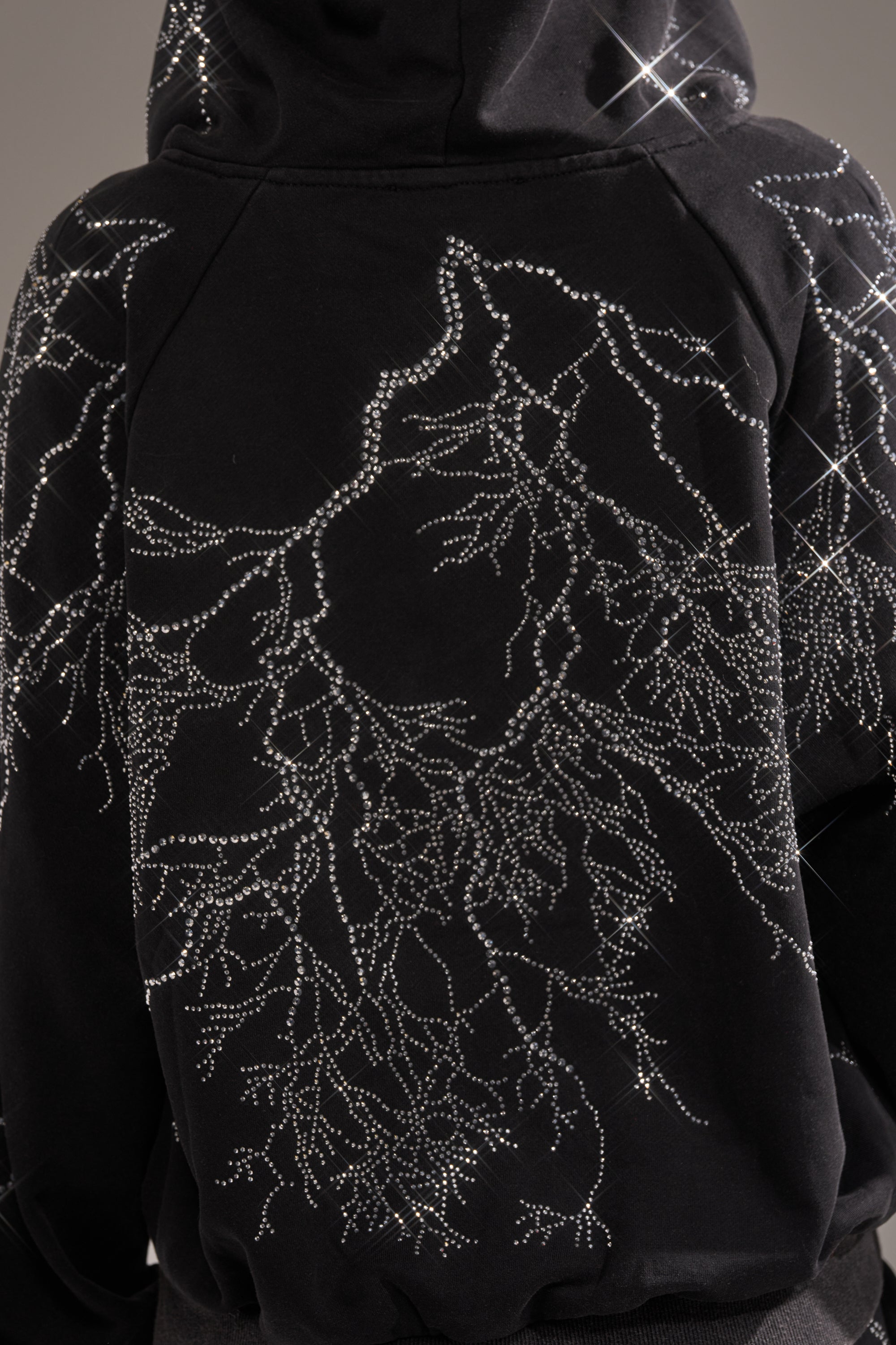 The ELECTRIC LOVE RHINESTONE ZIP UP SWEATSHIRT features sparkling rhinestones in an intricate, branching pattern resembling tree limbs or lightning, creating a shimmering effect on this oversized black sweatshirt. 6