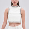A woman in the SPARKLE QUEEN BLOUSE with rhinestone embellishments and matching high-waisted pants holds a small clutch against a plain light gray background.