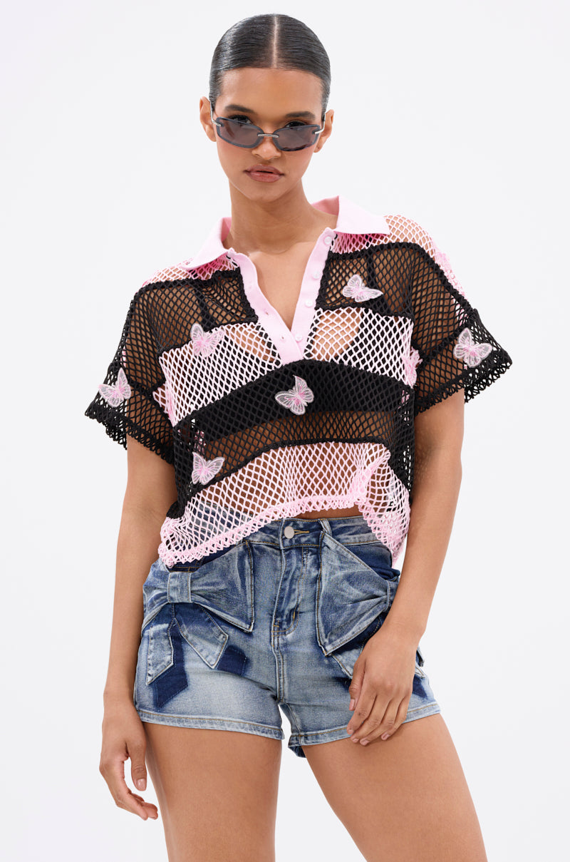 A woman poses confidently against a plain white background, wearing the FLY WITH ME STRIPE OVERSIZED TEE styled with sunglasses and denim shorts with bow details.