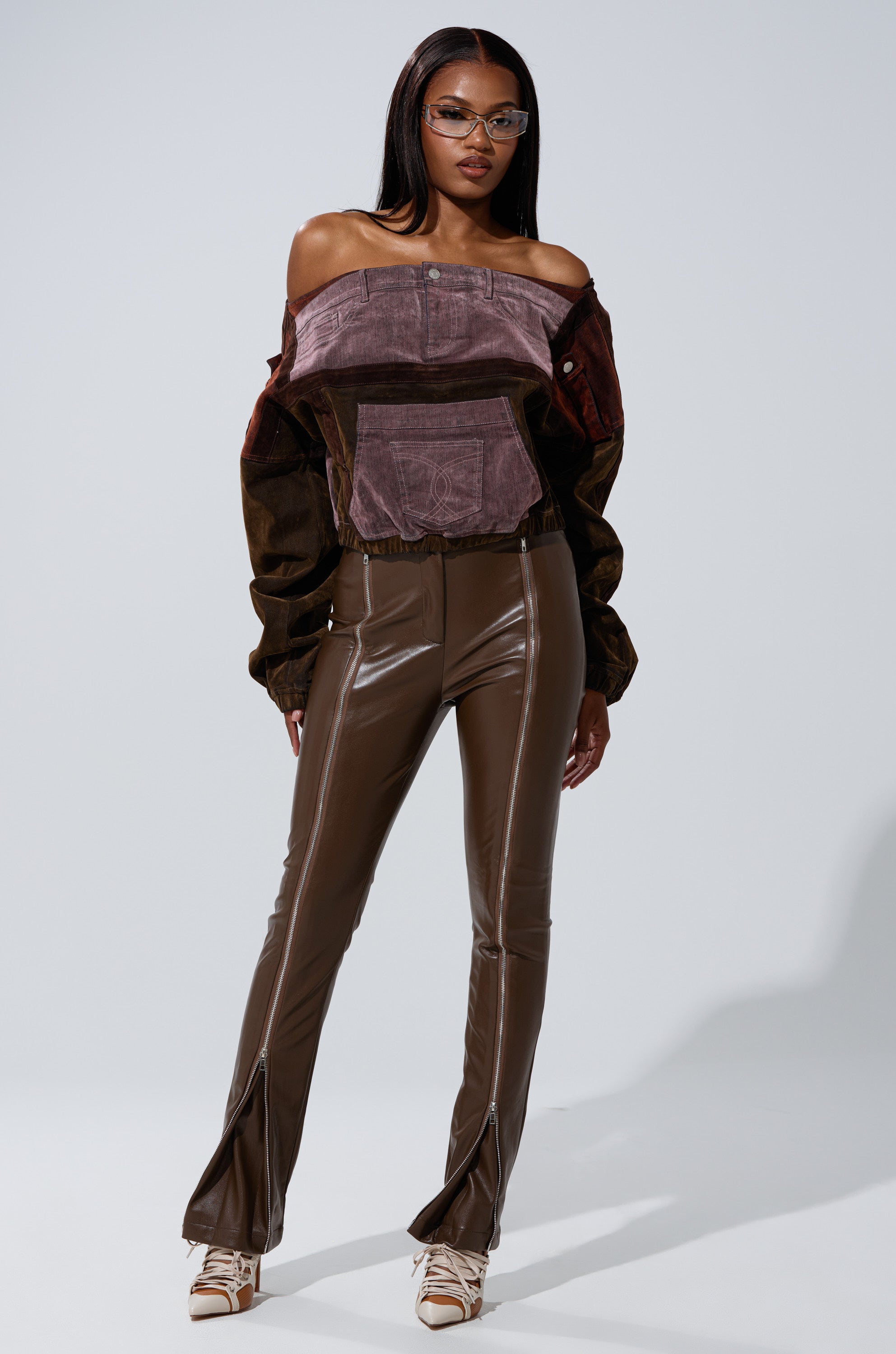 A woman stands confidently in the PATCH ME UP MINERAL WASHED SWEATSHIRT IN PURPLE, paired with beige heels and clear-frame glasses, against a plain light background. 4