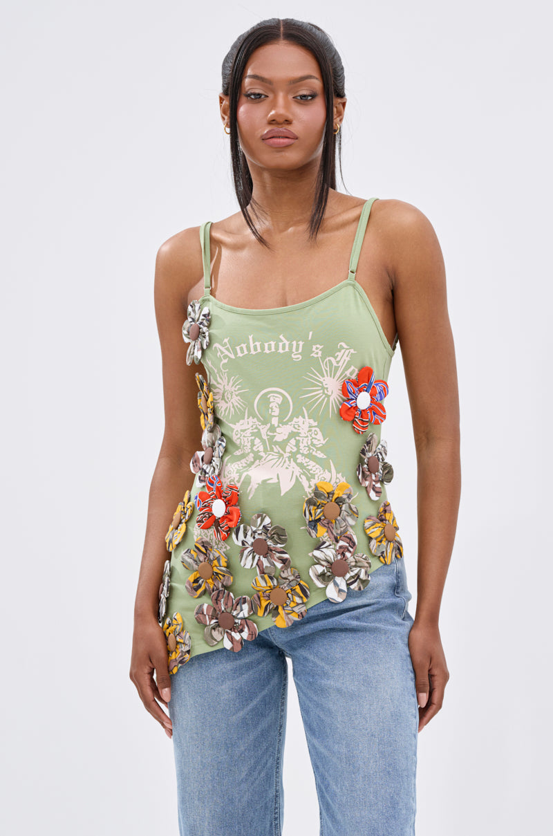 A woman wears the FOR THE FREE FLORAL EMBELLISHED TOP with "Nobody's" graphic text, paired with light blue jeans, standing against a plain white background.