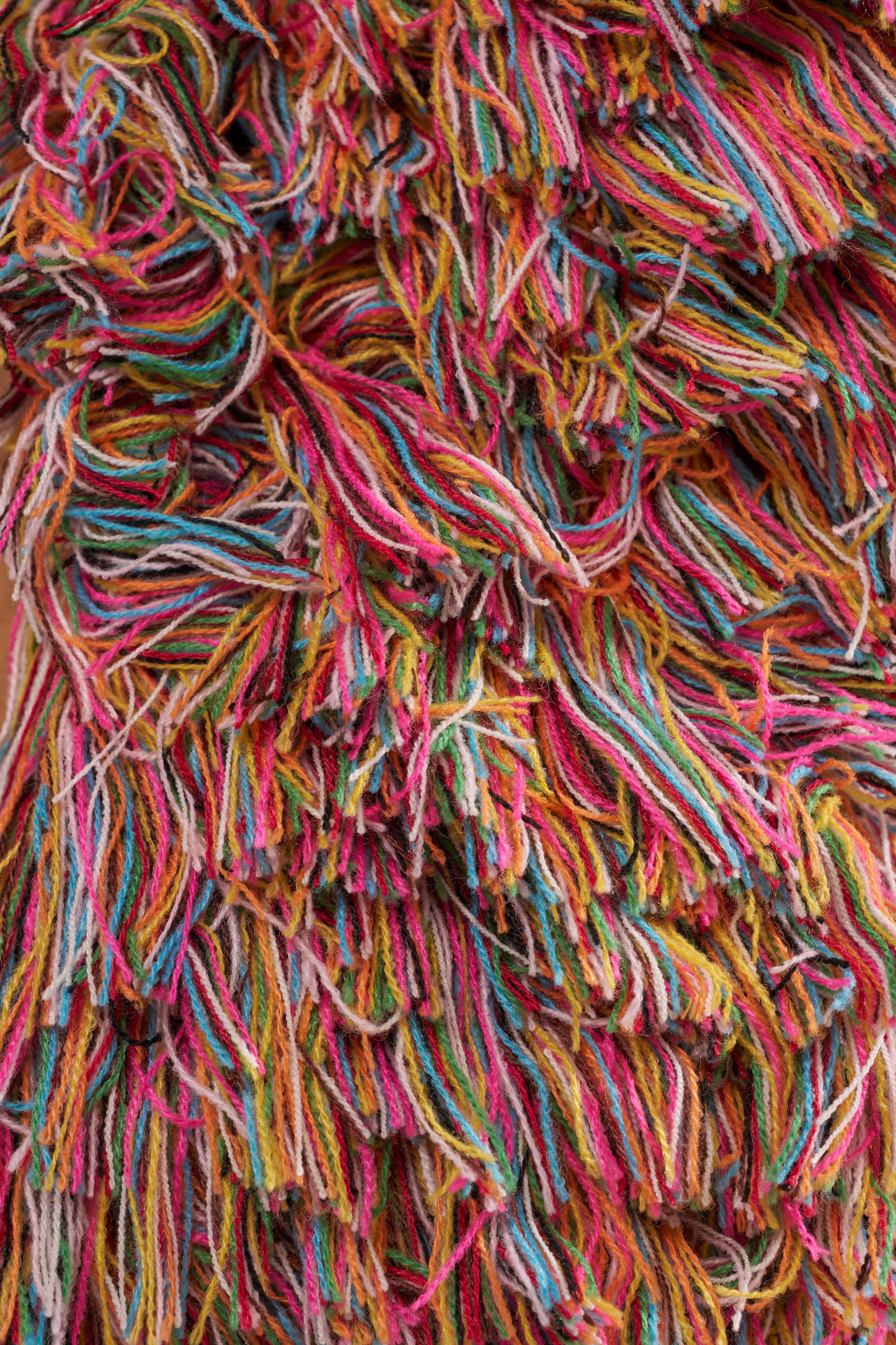 Close-up of THE ONE FRINGE BLOUSE, featuring vibrant red, orange, yellow, green, blue, and pink fringe strands—tangled and layered like a rainbow—creating a lively pattern ideal for festival wear. 7