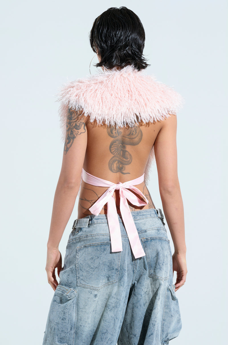 Facing away from the camera, they wear the JAMEELA TOP, a fuzzy pink faux fur halter with an open back and pink ribbon ties, revealing tattoos. The look is completed with loose, cropped jeans with pockets against a plain white background. 4