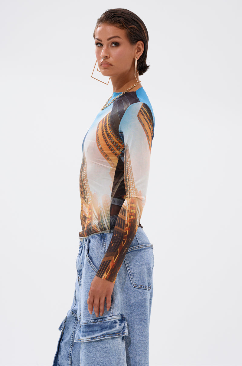 A woman with short, wet-look hair models the BIG CITY LONG SLEEVE MESH TOP and light blue baggy cargo jeans, standing in profile against a plain white background. 3