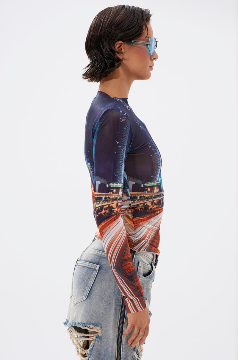 A woman with short dark hair and sunglasses stands in profile against a white background, wearing the CITY LOVER MESH LONG SLEEVE top and light blue distressed jeans with rips and frayed edges. 3