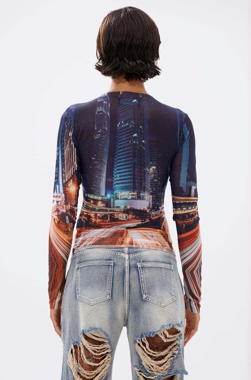 A person with short dark hair, seen from behind, wears the CITY LOVER MESH LONG SLEEVE featuring a curve-hugging nighttime cityscape graphic, paired with light blue, heavily distressed jeans with large back tears. 4