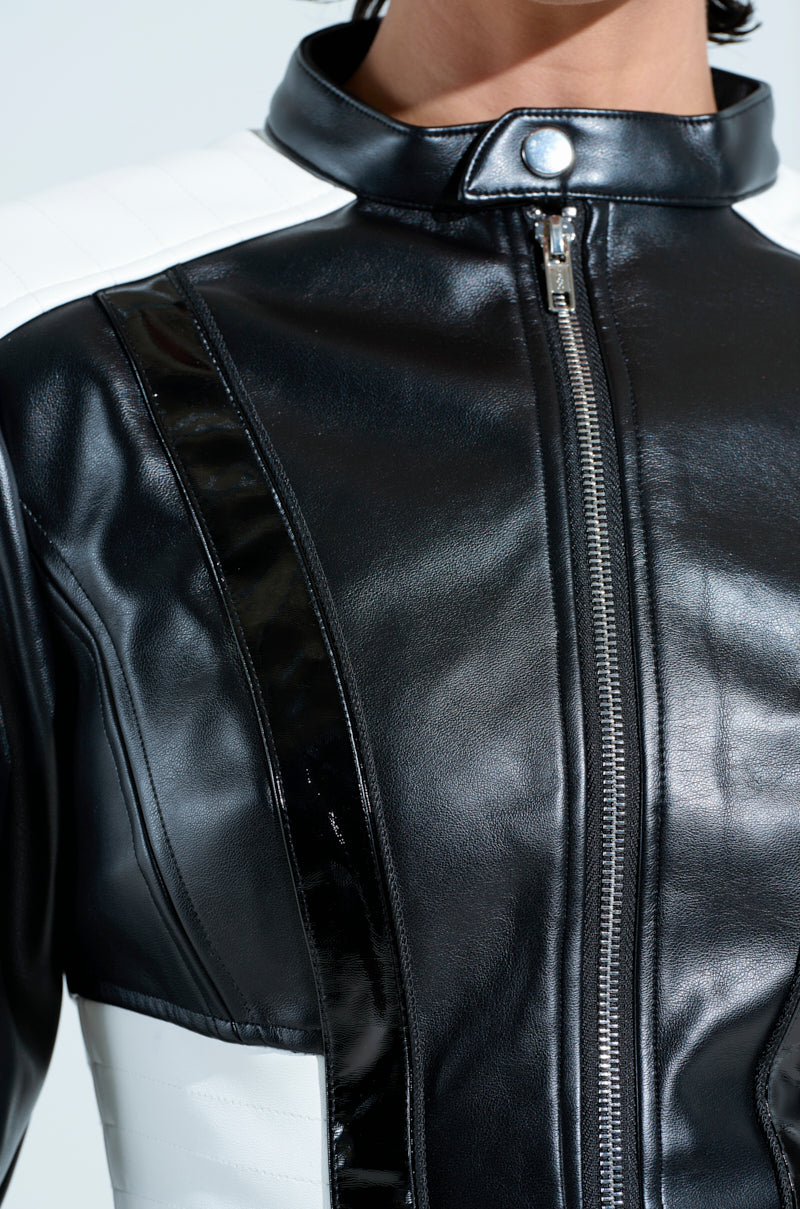 Close-up of the UP TO NO GOOD BODYSUIT in black and white faux leather, highlighting a shiny black zipper, silver snap button at the collar, and contrasting panels. The visible texture and stitching showcase a sleek, modern design similar to a paneled jacket.