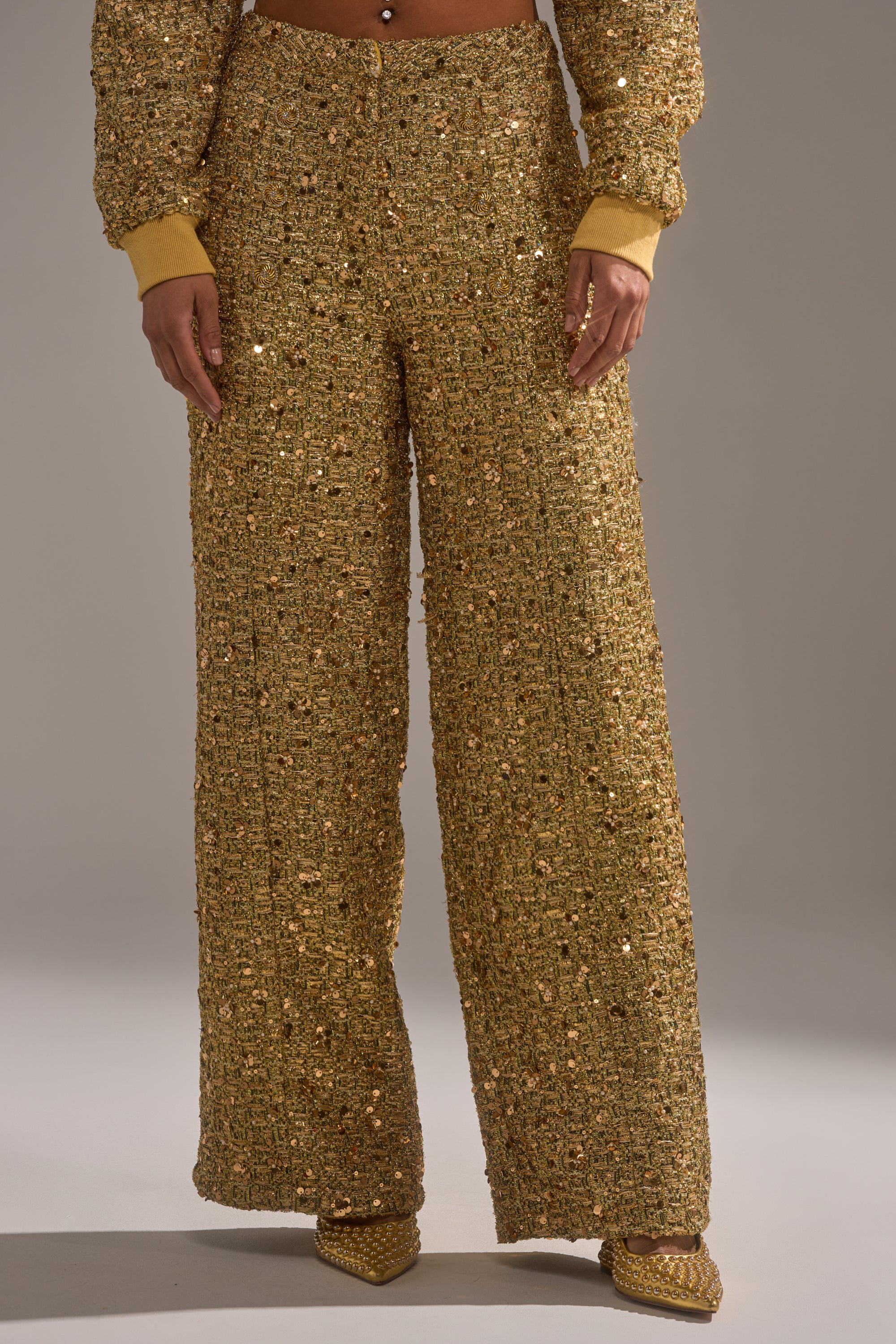 A person wearing the PRETTY IN GOLD STRAIGHT LEG PANT and matching jacket with pointed gold shoes stands against a plain background, showing only their lower half.