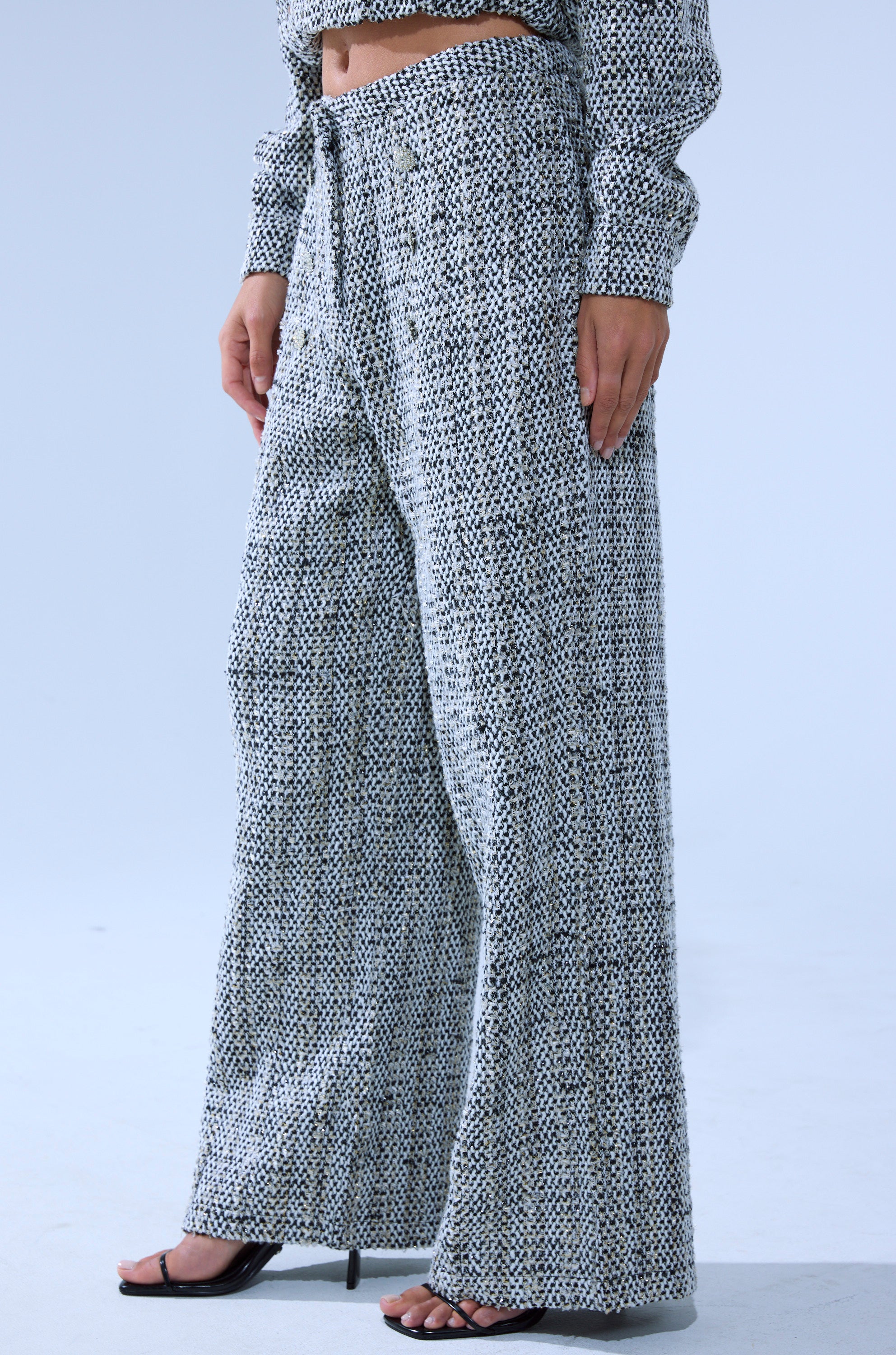 A person wearing DRESSY VIBES TWEED PANT in a high-rise, wide-leg silhouette with a matching long-sleeve top and black open-toe heeled sandals stands against a light background. 3