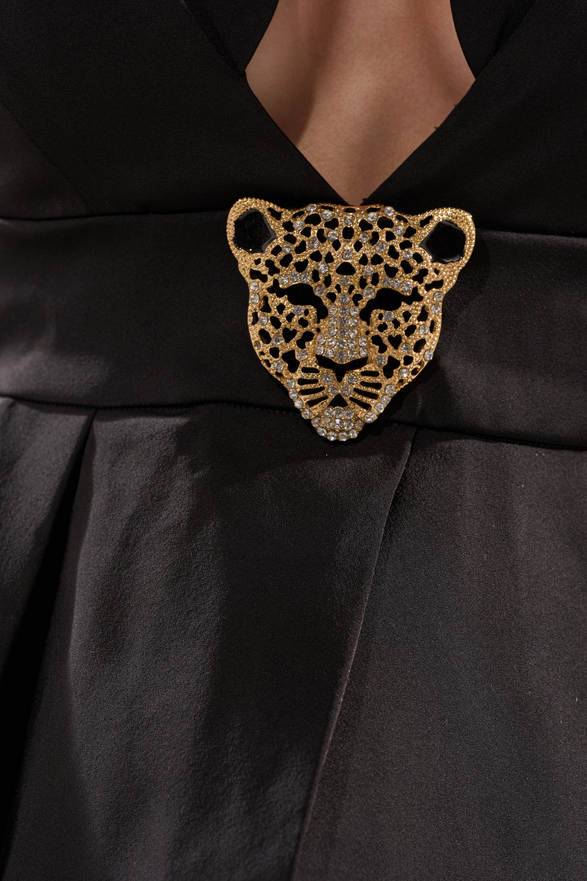 A close-up of a person wearing the FIERCE BLOUSE, adorned with a large, ornate gold and diamond leopard head brooch pinned at the chest.