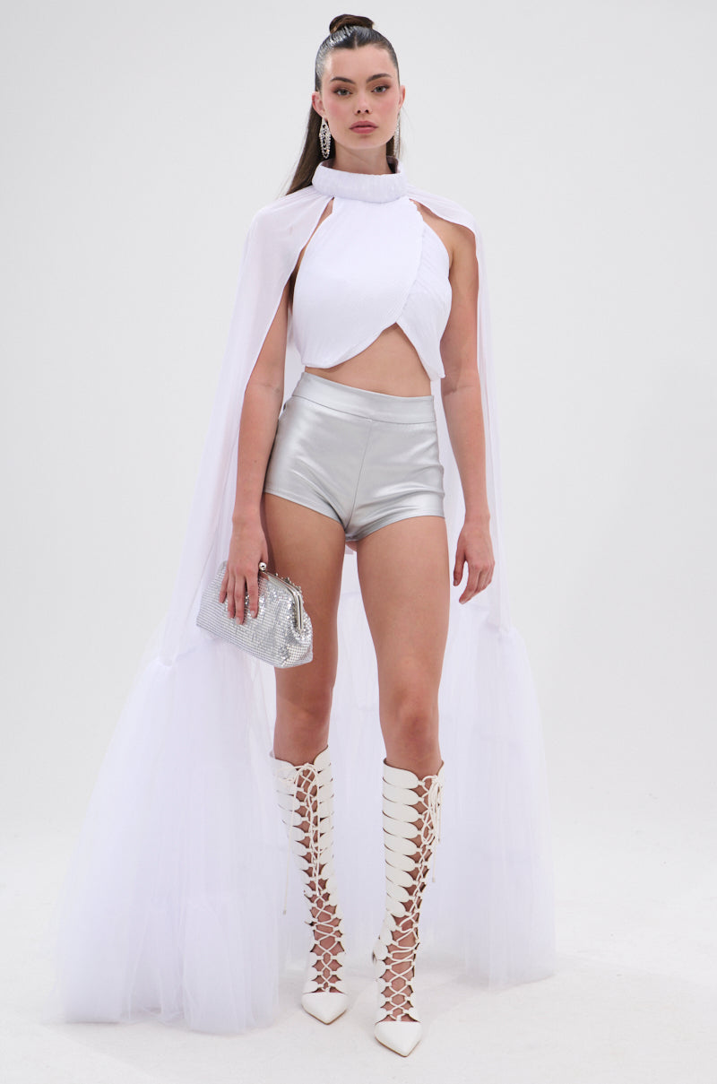 A woman stands against a plain white background wearing the DONT WASTE MY TIME BLOUSE, paired with metallic silver shorts, knee-high lace-up white boots, and holding a silver clutch bag. 3