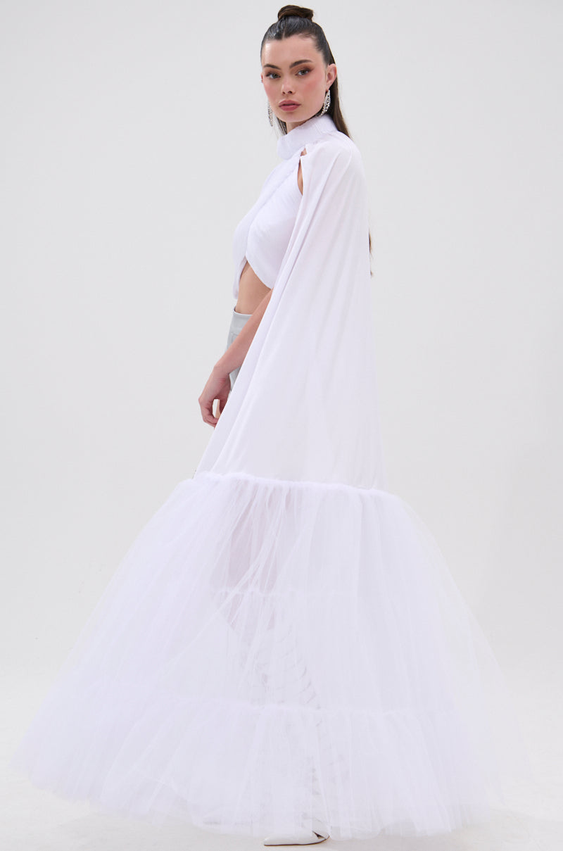 A woman stands in profile wearing the DONT WASTE MY TIME BLOUSE, a flowing white top with voluminous gathered sleeves. Her slicked-back hair and the plain white background highlight the blouse's elegant, ethereal style. 4