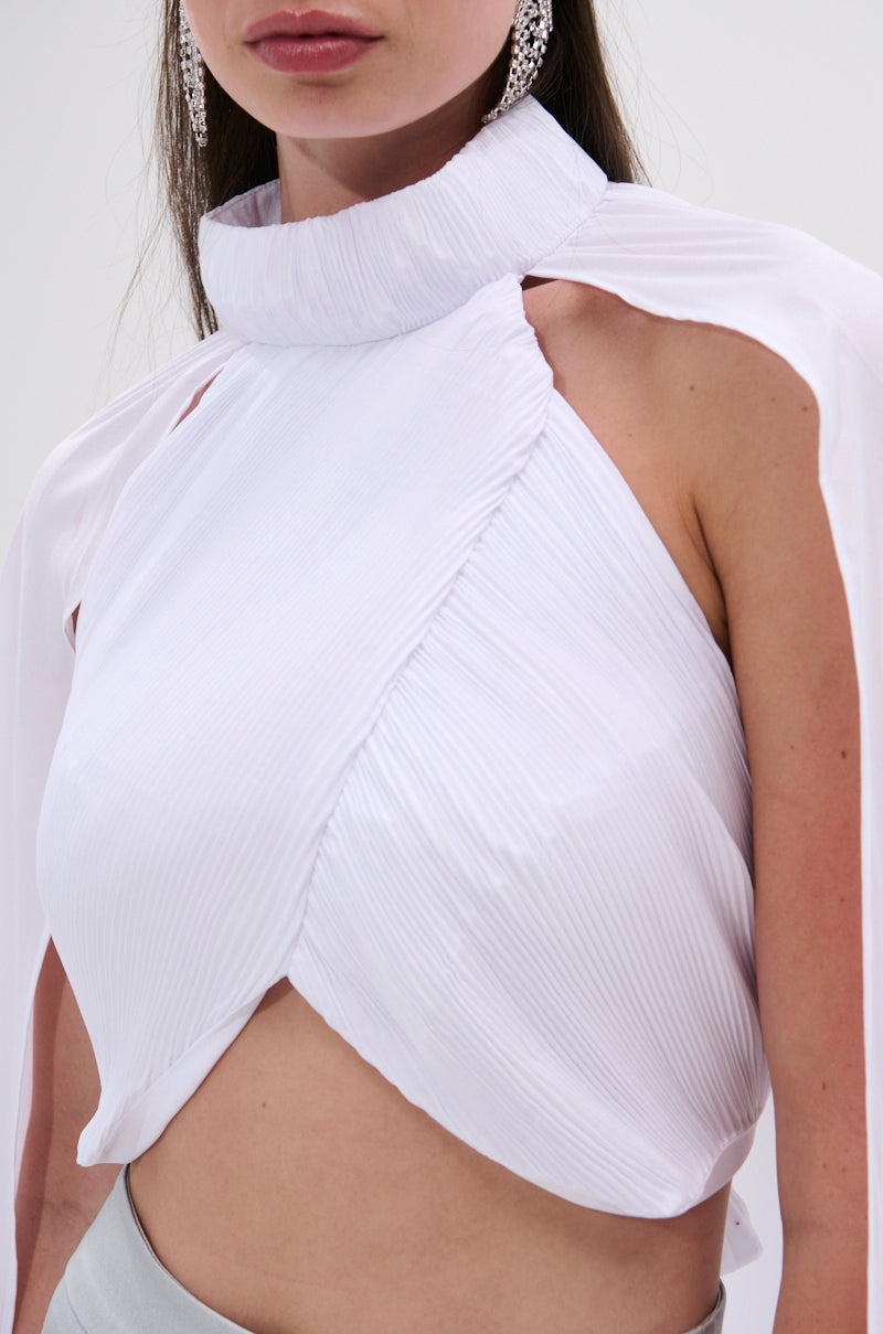 A woman with long brown hair and dangling earrings wears the DONT WASTE MY TIME BLOUSE—a sleeveless, sheer white mesh top featuring a high neck, pleated detail, draped asymmetry, and midriff-baring design. 8