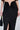 Wearing the DREAM CATCHER MAXI SKIRT IN BLACK, which features a high-rise fit, deep V-shaped ruched detail, and thigh-high slit, while carrying a black handbag with a gold handle.