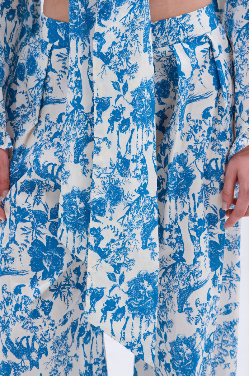 Close-up of a person wearing the DOLLED UP PALAZZO PANT in a blue and white vintage rose print. The textured fabric features a high-rise waistband, matching top, and partially visible hands.