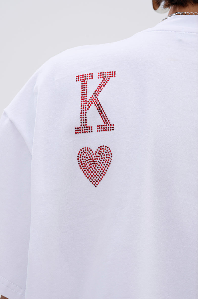 The KING OF HEARTS OVERSIZED TEE IN WHITE features a bold red "K" and heart in rhinestones on the back, shown worn by a model facing away from the camera.