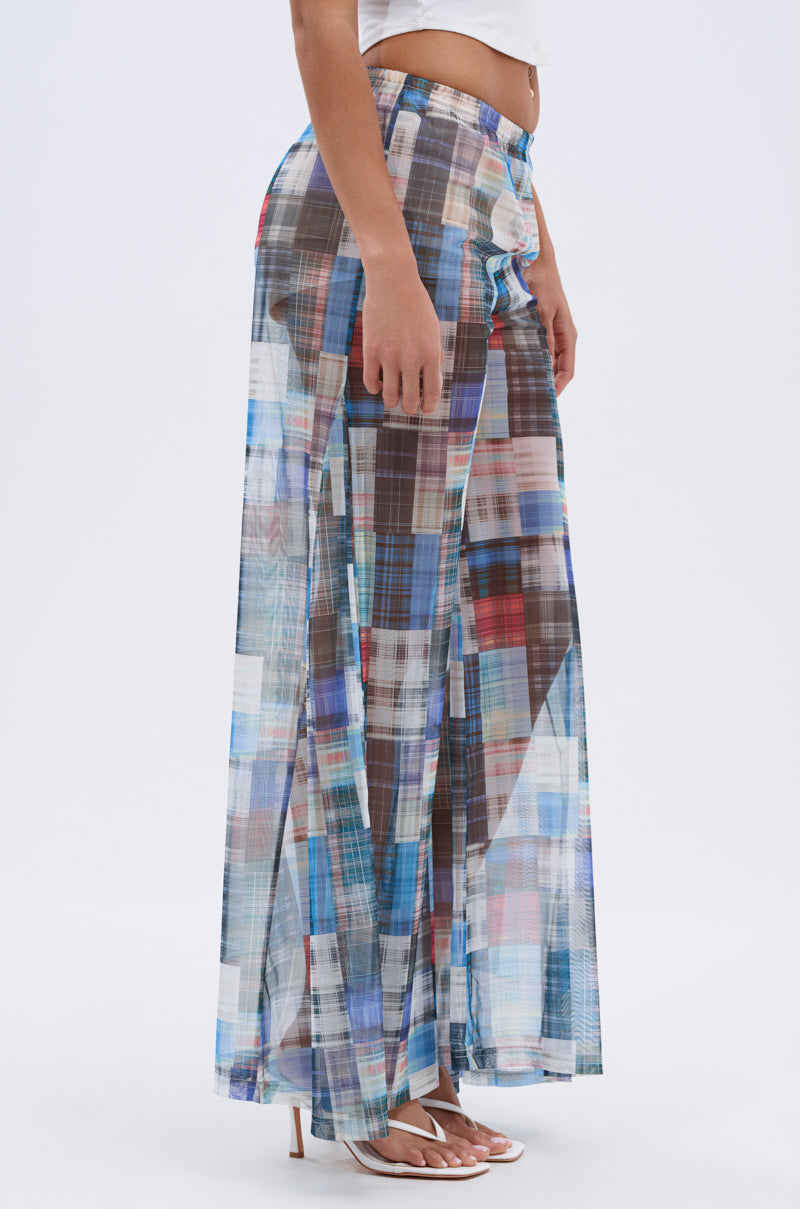 A woman models the LIVING THE LIFE PLAID MESH PALAZZO PANT in blue, brown, and white plaid mesh with a high-rise, wide-leg fit, paired with a white crop top and heeled sandals against a plain light background.