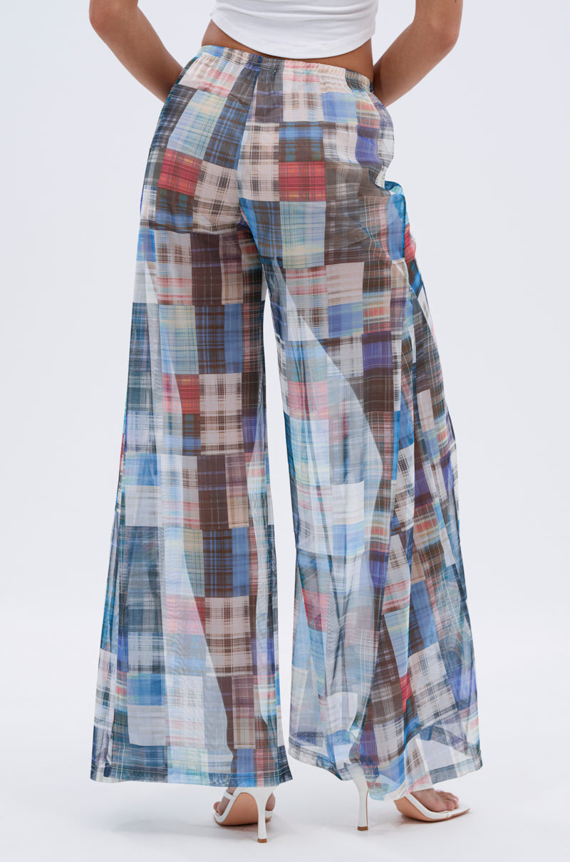 A person models the LIVING THE LIFE PLAID MESH PALAZZO PANT, featuring a high-rise fit and wide-leg silhouette, paired with white heels and a cropped top, shown from the back against a plain background.