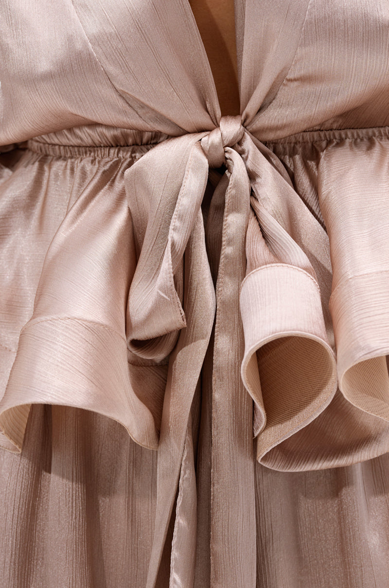 Close-up of the ELEGANT PEPLUM TIE FRONT BLOUSE in shiny light pink or champagne, featuring a waist tie bow and flowing ruffled satin details for an effortlessly elegant look. 6